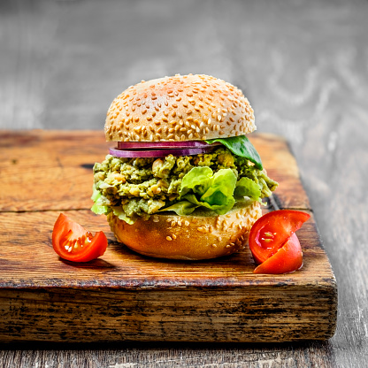 Chickpea and avocado vegetarian burger on wooden cutting board