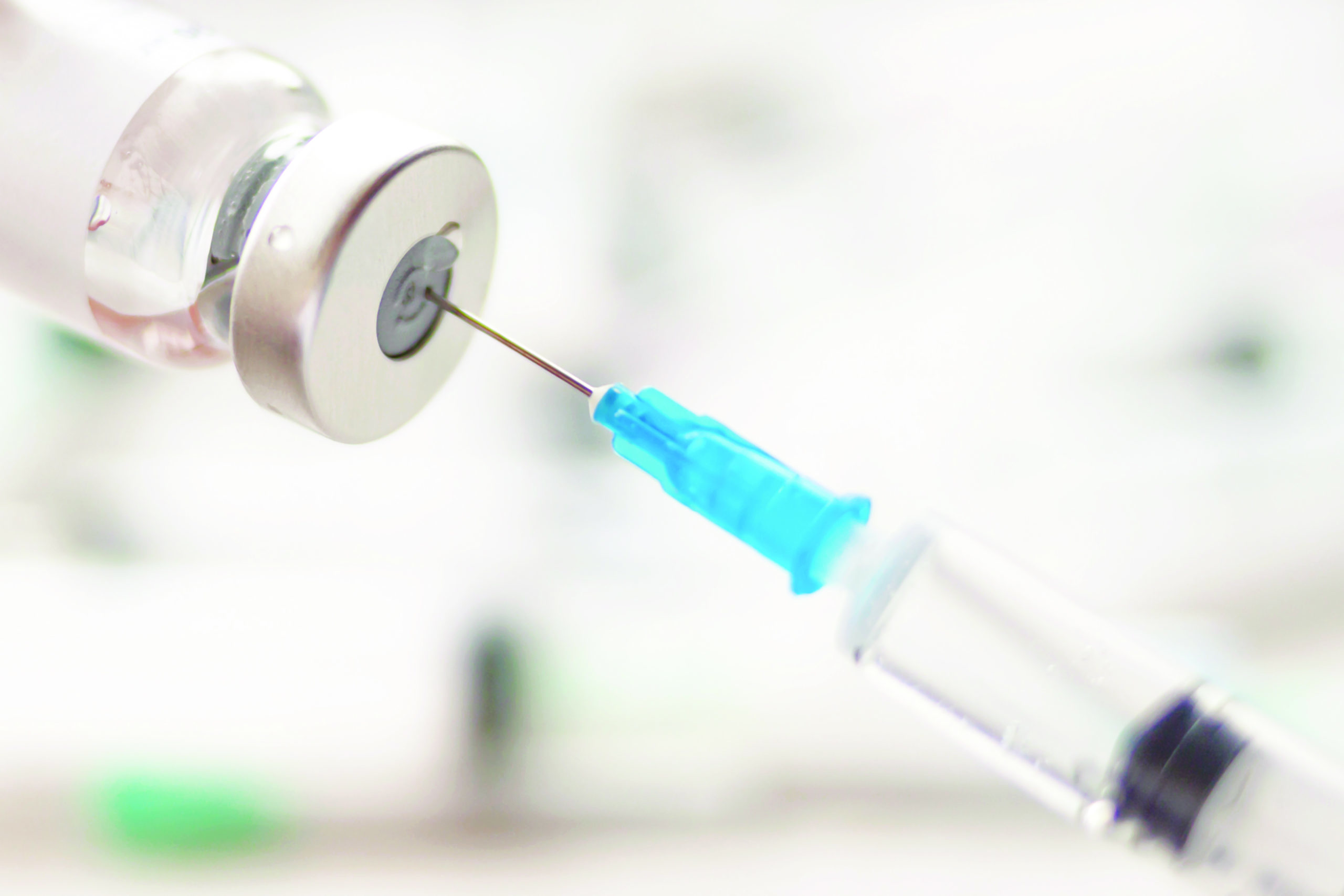 Dialing medicine into syringe from glass bottle. Ampoule and syringe needle close-up.