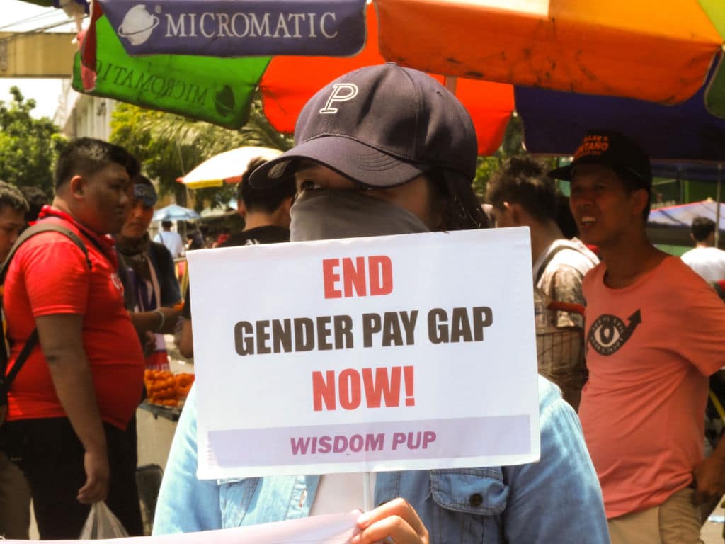 A protester seen holding a placard that says end gender pay