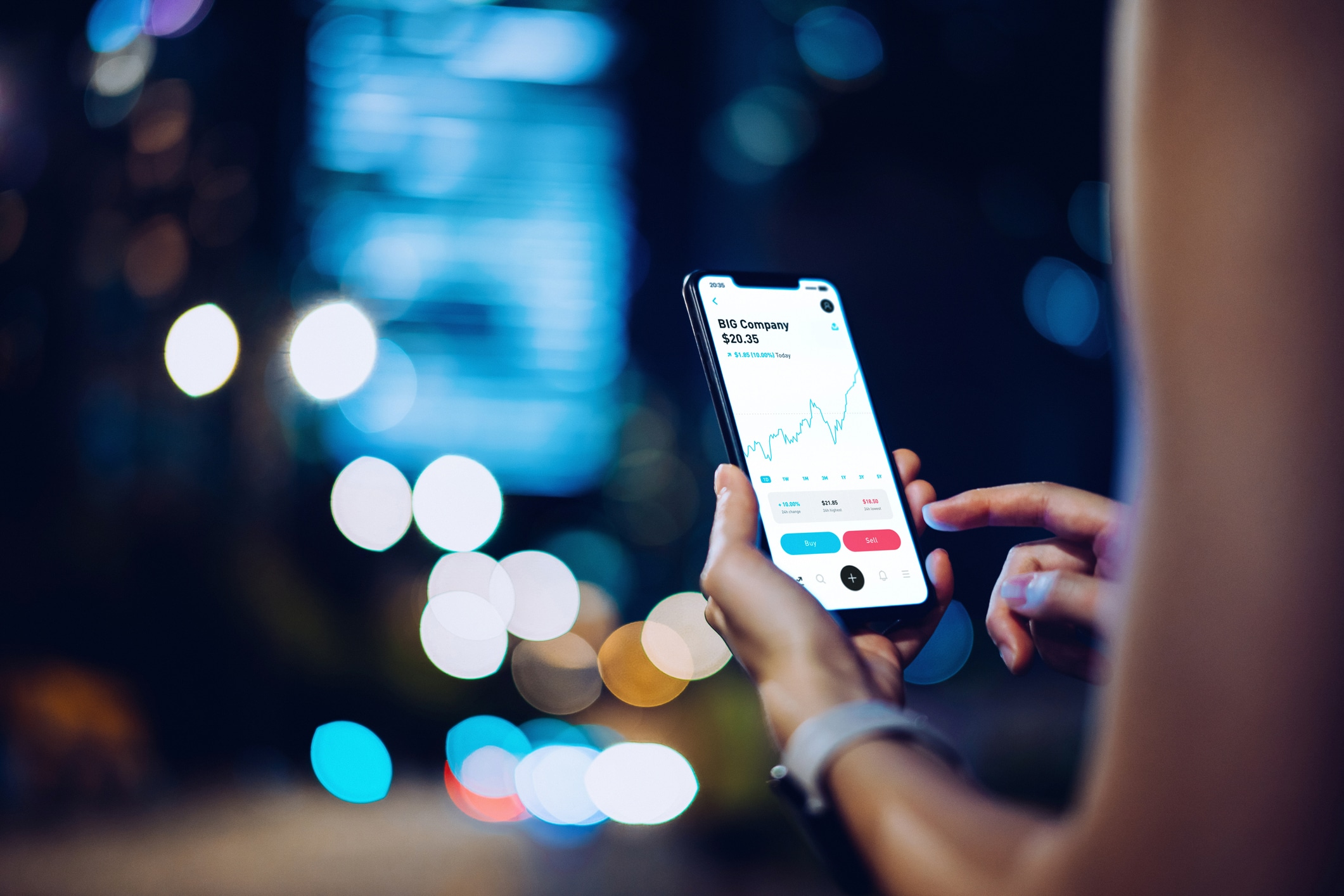 Close up of businesswoman checking financial stock market analysis with mobile app on smartphone on the go, against illuminated corporate skyscrapers in financial district at night. Financial investment, stock market and exchange, accounting concept