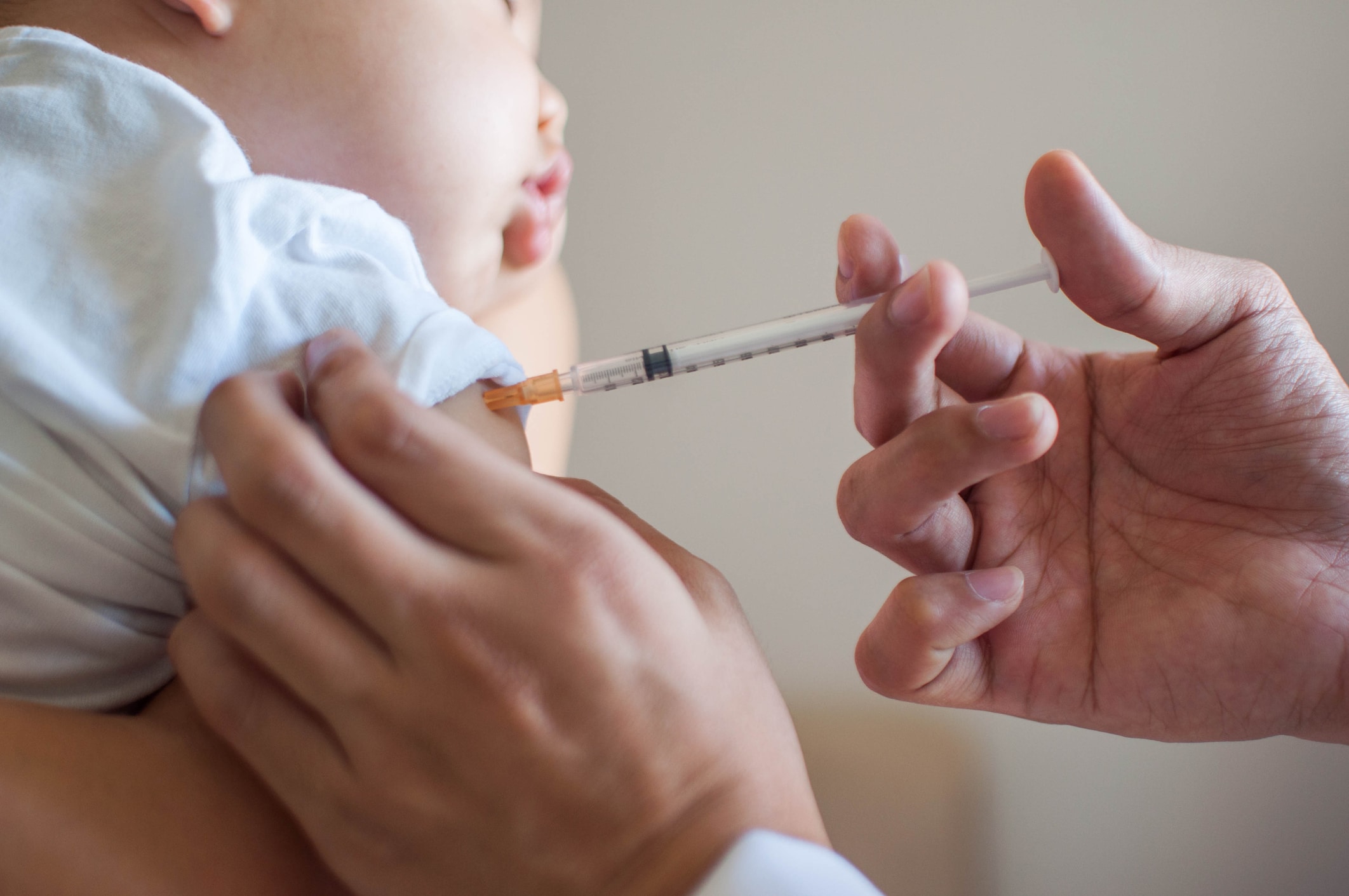 A doctor is injecting a vaccine to a baby boy