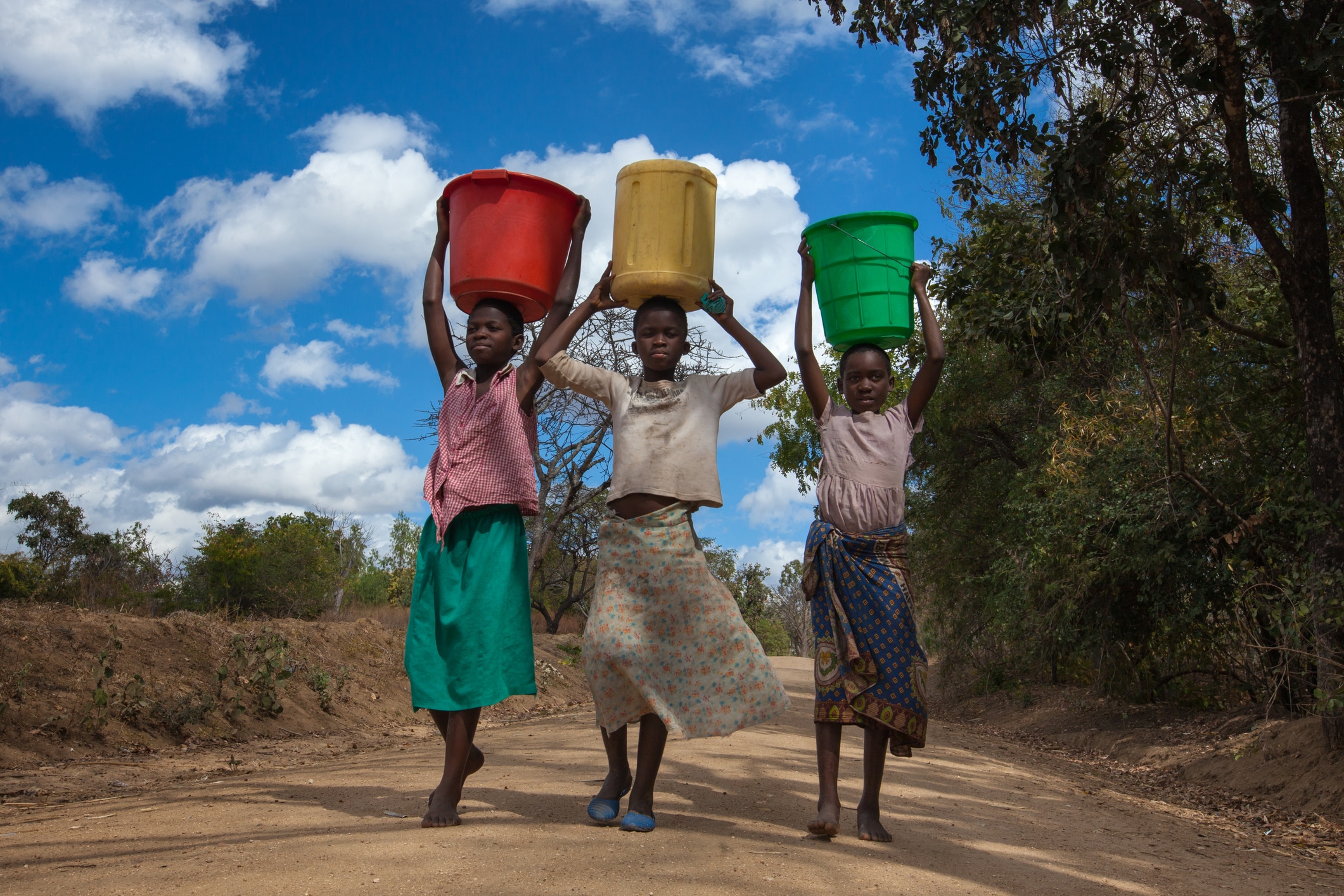 Girls carrying water buckets at a borehole in Malawi