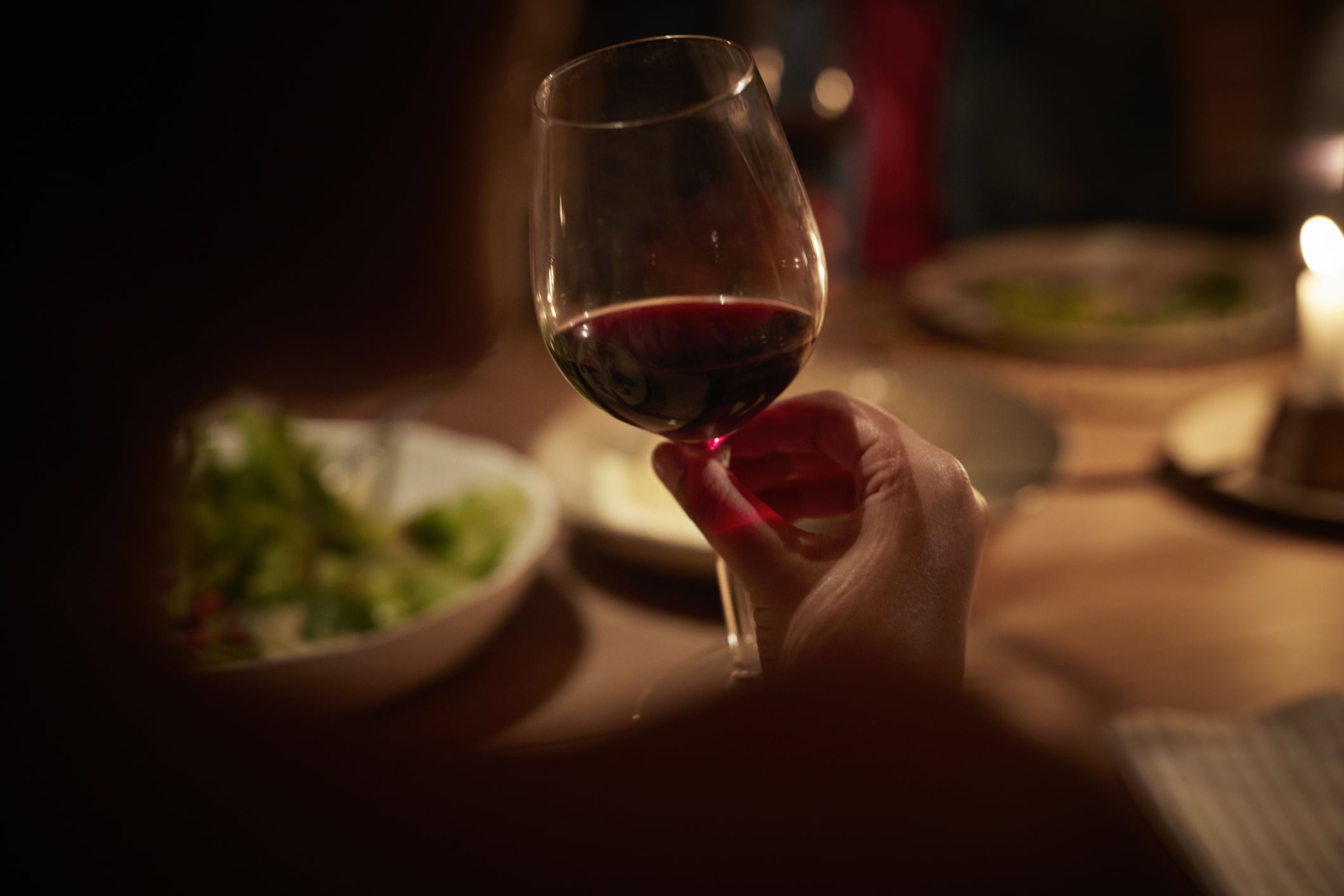Close-up of hand holding wine glass, at late dinner