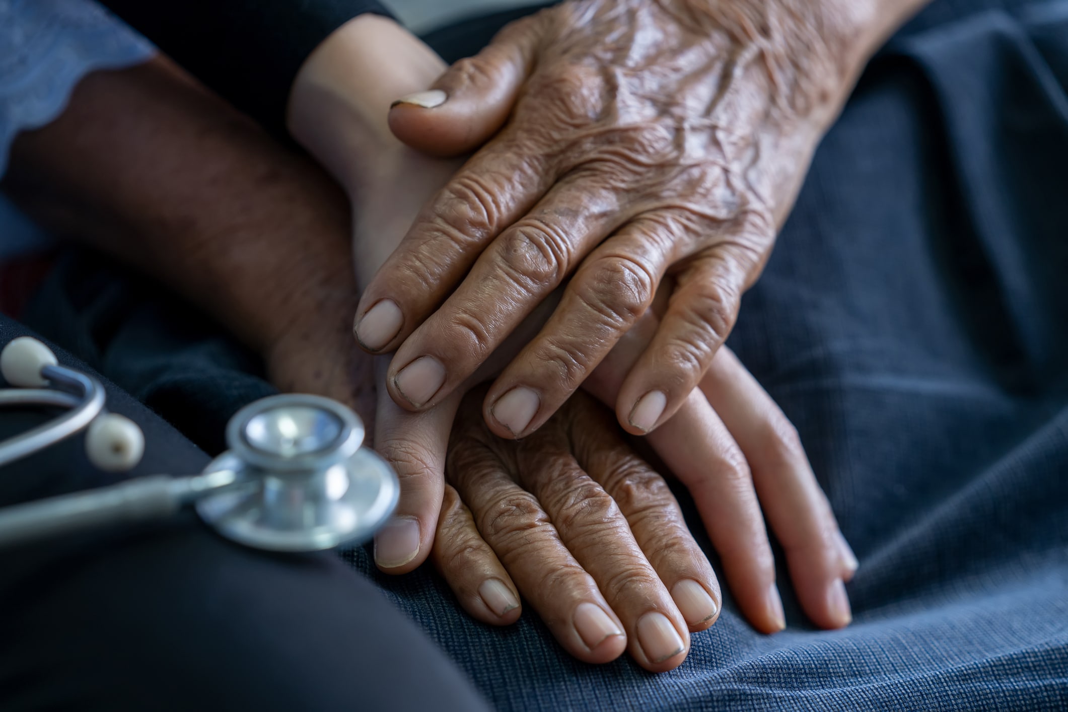Close up of young nurse holding old man’s hands and encourage him.