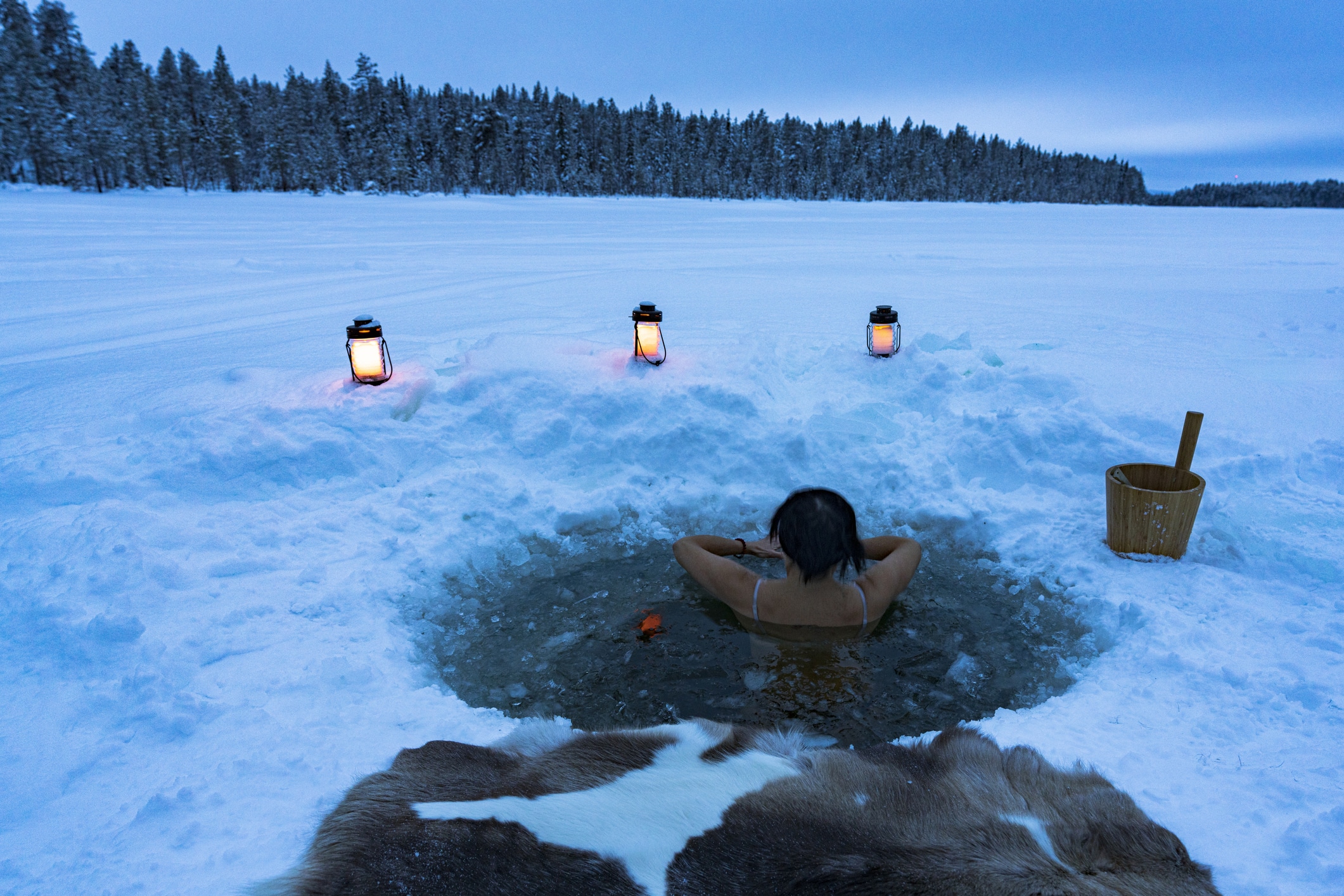 Woman enjoying cold baths in a ice hole, Lapland