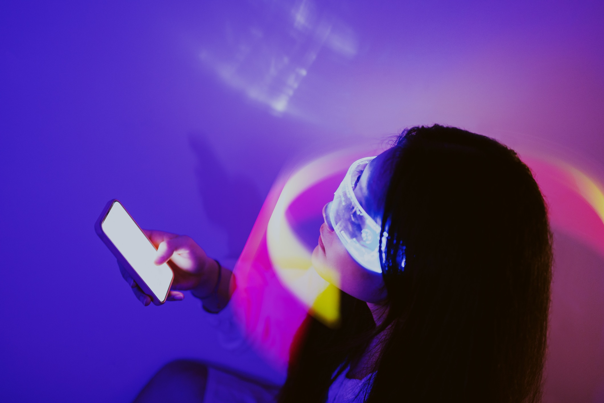 Asian woman using smartphone surrounded by beams of light. Metaverse and Artificial Intelligence