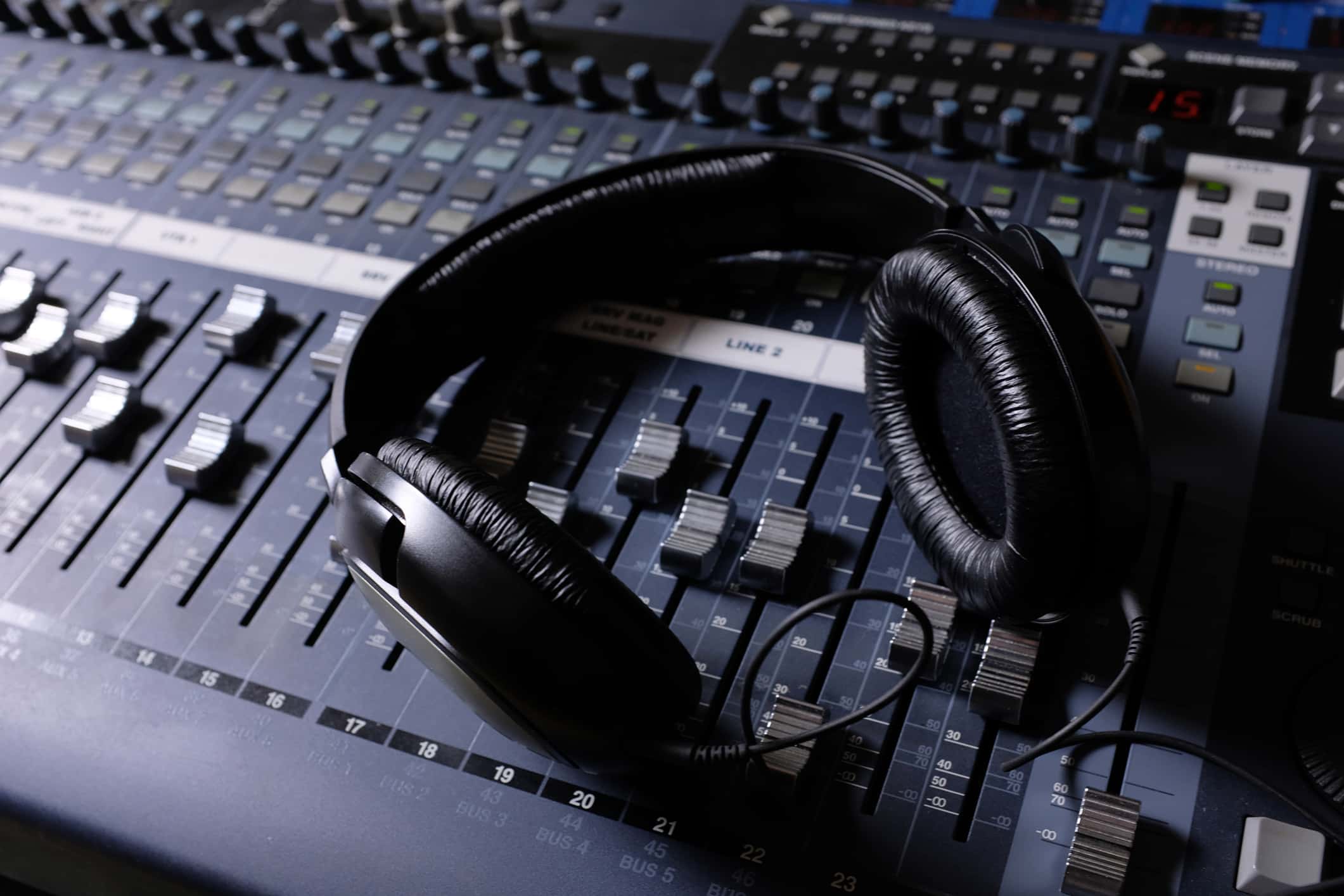 Headphones, Amplifying Equipment, Studio Audio Mixer Knobs And Faders. Sound Engineering Equipment. Selective Focus. The photo is covered with sand and noise. Wireless and electronic technologies. Equipment in a nightclub, on television, radio studio.