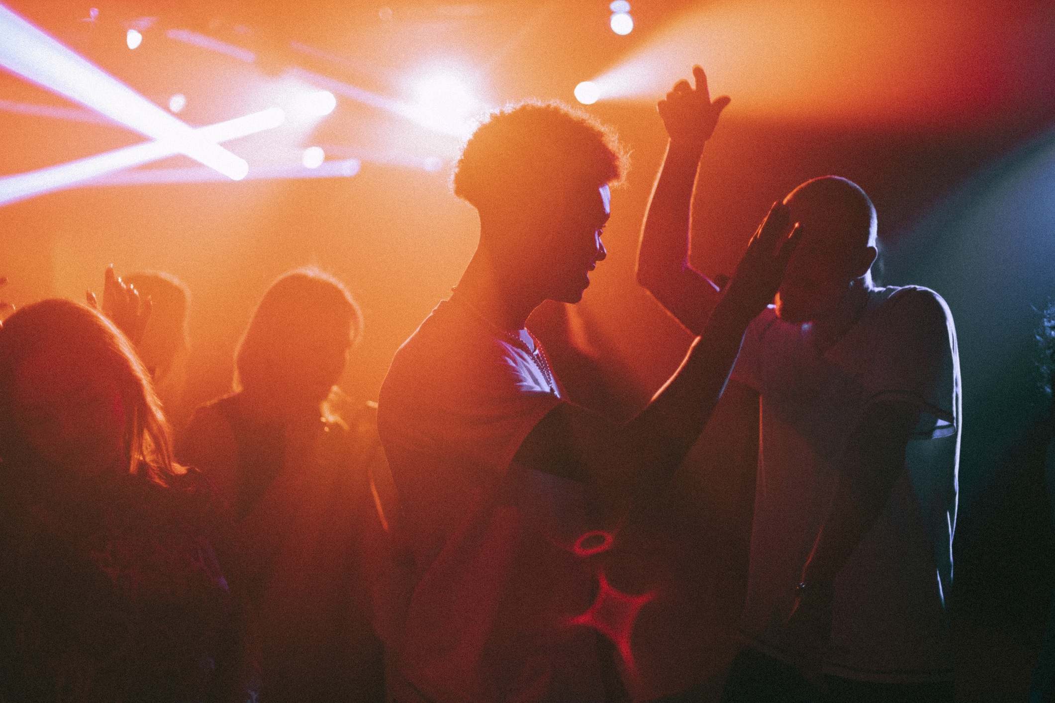 Young men and women dancing against illuminated red spotlights at nightclub