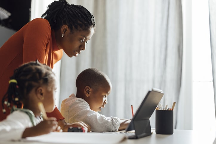 Serious Mother Helps her Children To Do Their Homework in a Living Room