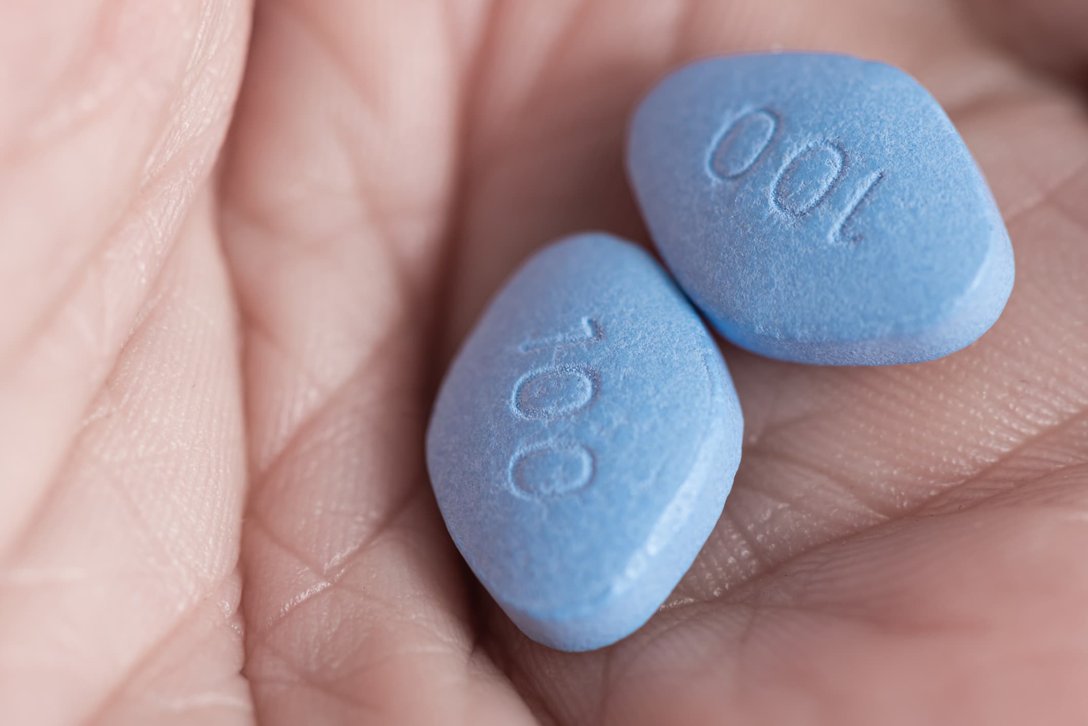 Two blue pills viagra in male hand. Medicine concept of men health, medication for erection, treatment of erectile dysfunction