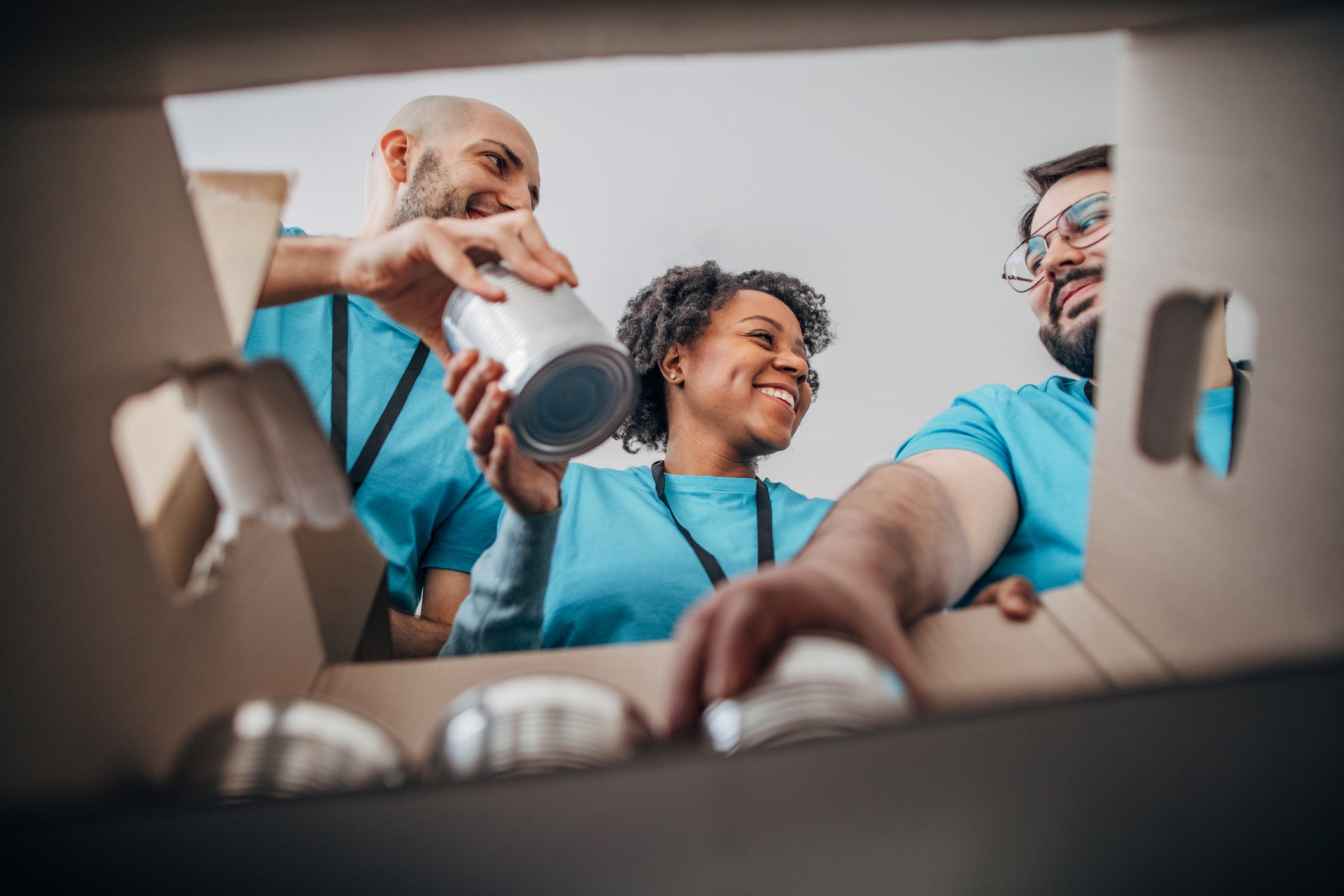 Diverse volunteers packing donation boxes with canned food in food bank