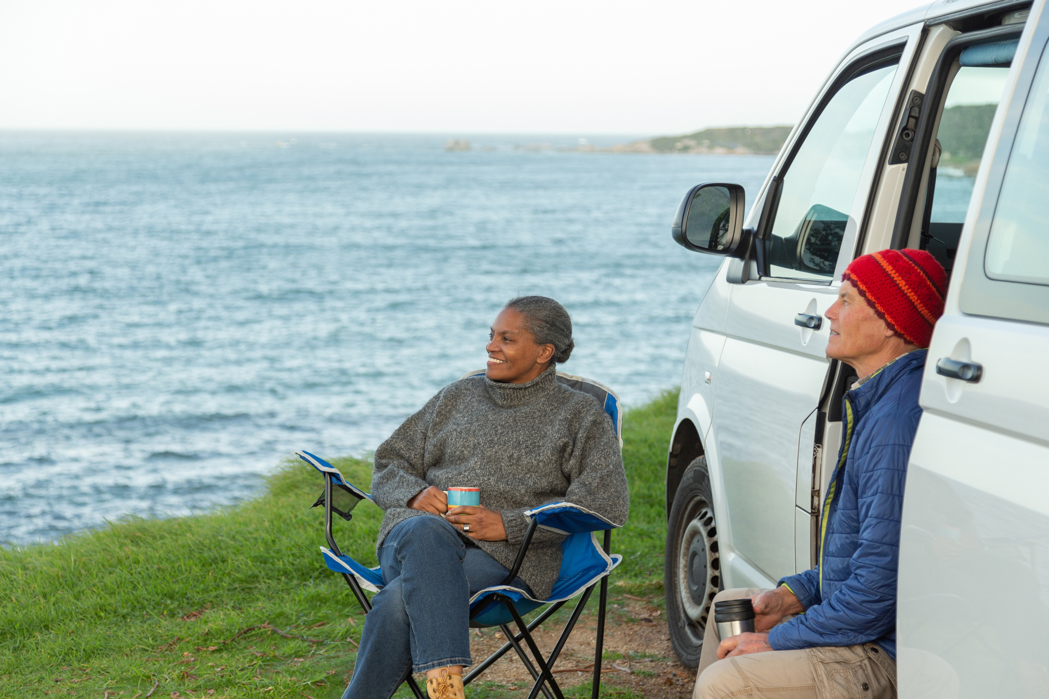 Senior couple enjoying time by the sea with their camper van